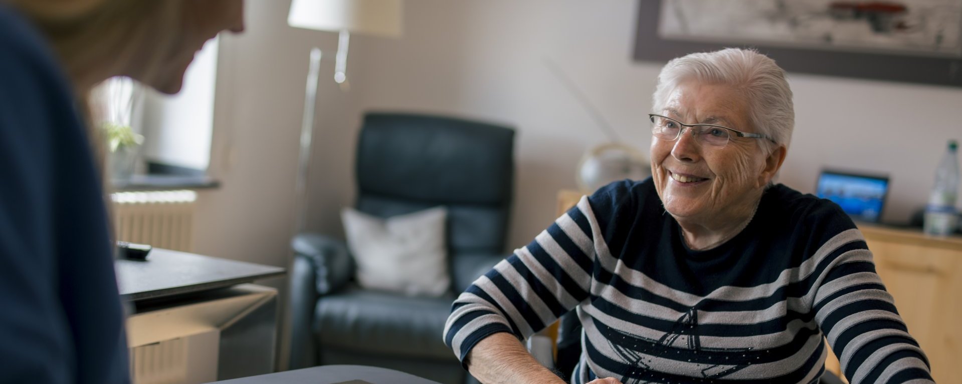 Eine Bewohnerin unterhält sich lachend mit einer Mitarbeiterin.