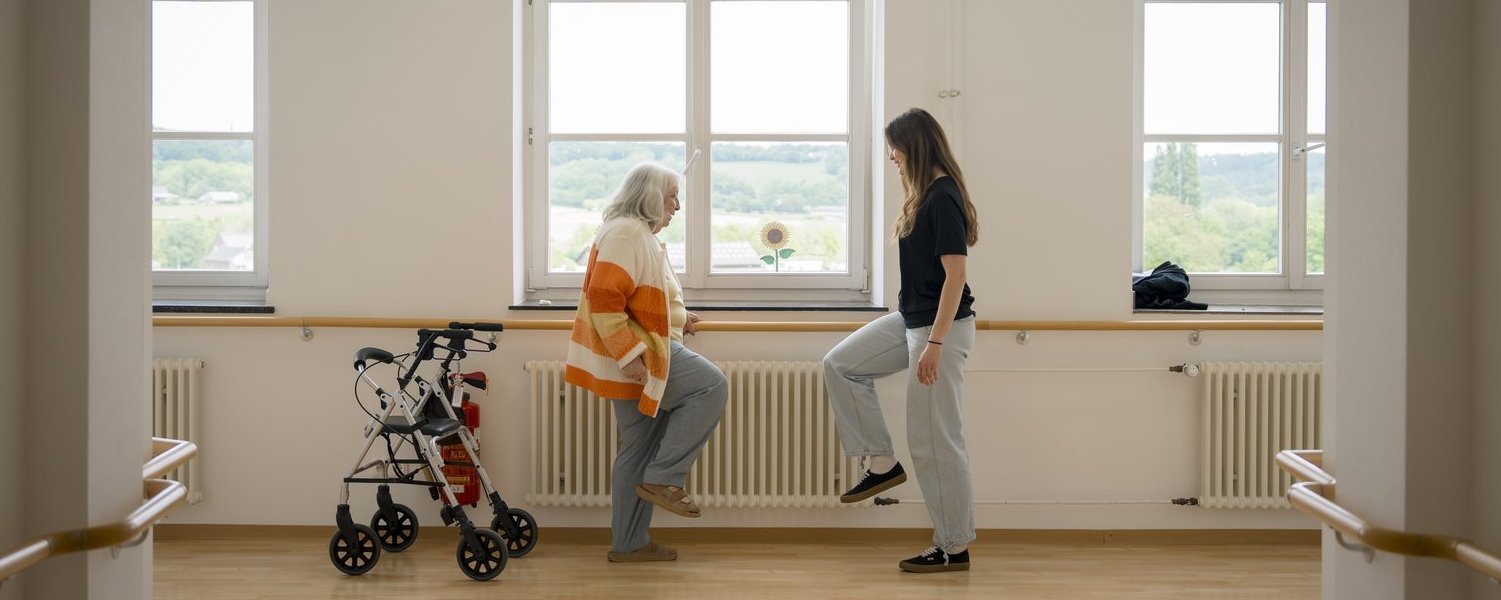 Eine Bewohnerin macht gemeinsam mit einer Mitarbeiterin des Hauses St. Raphael Gleichgewichtsübungen.