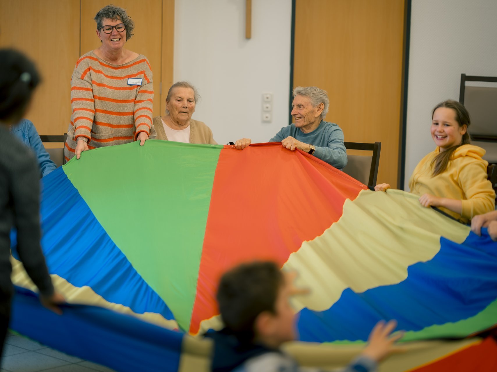 Eine Gruppe von Bewohnenden, Mitarbeitenden und Kindern spielt gemeinsam ein Spiel.