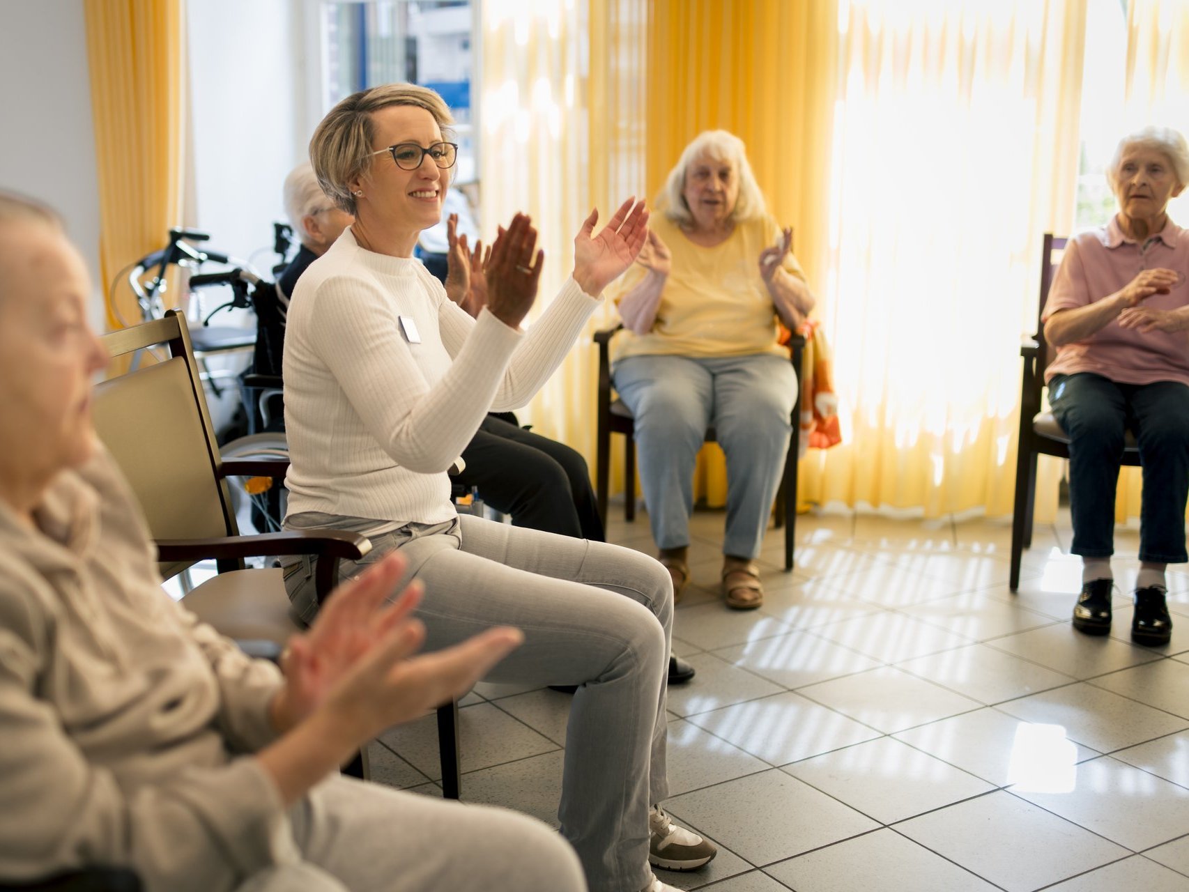 Eine Gruppe von Bewohnenden trainiert gemeinsam mit einer Mitarbeiterin mit kleinen Hanteln.